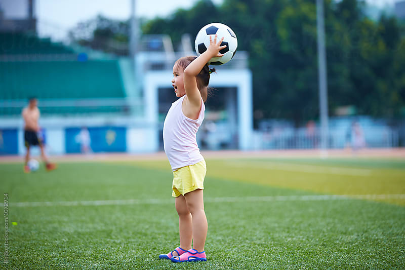 little asian or Chinese girl playing football outdoor in the football field