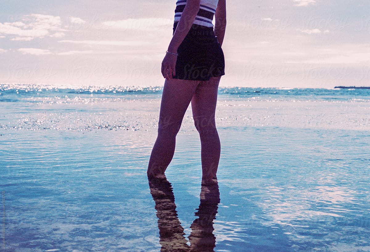 Girl standing in ankle-deep, beautiful, blue ocean water