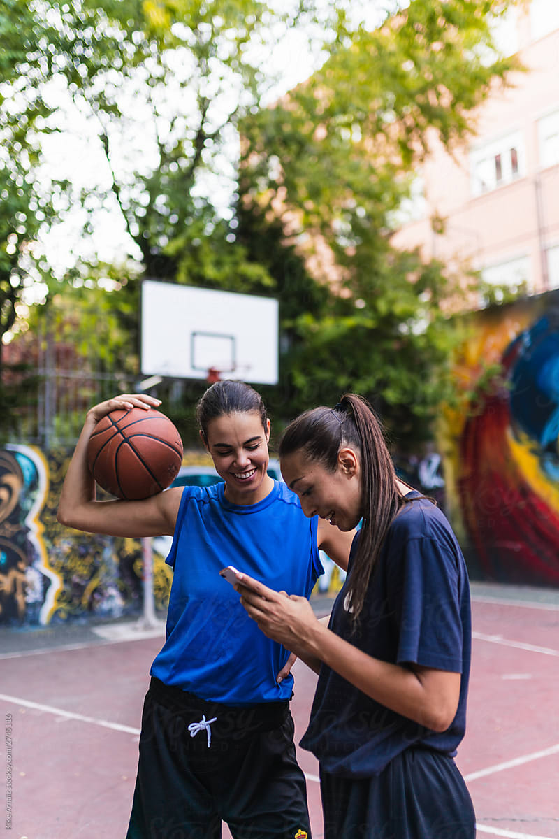 Two female basketball player using phone