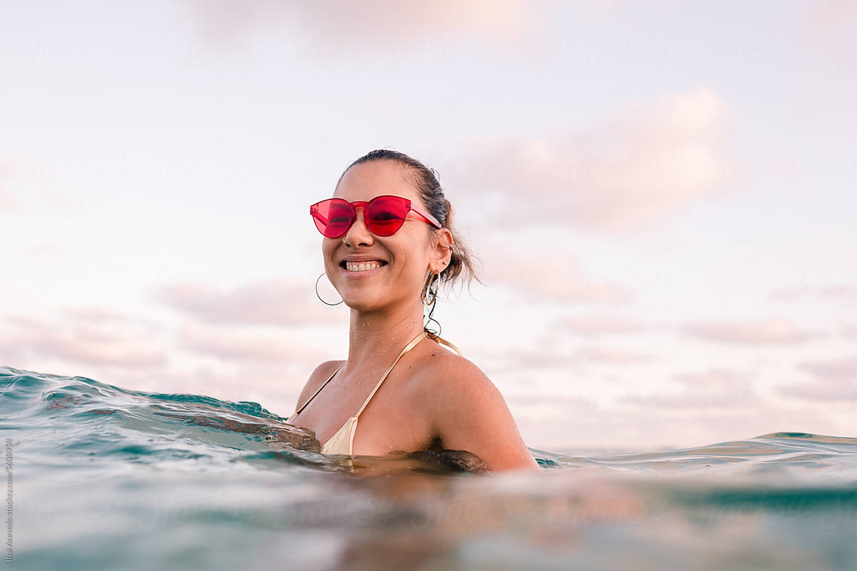 Cheerful woman in the sea with red sunglasses