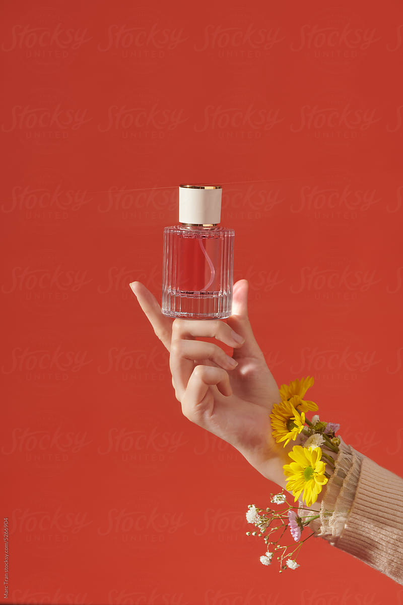 Female hand with wildflower bracelet takes jar of perfume