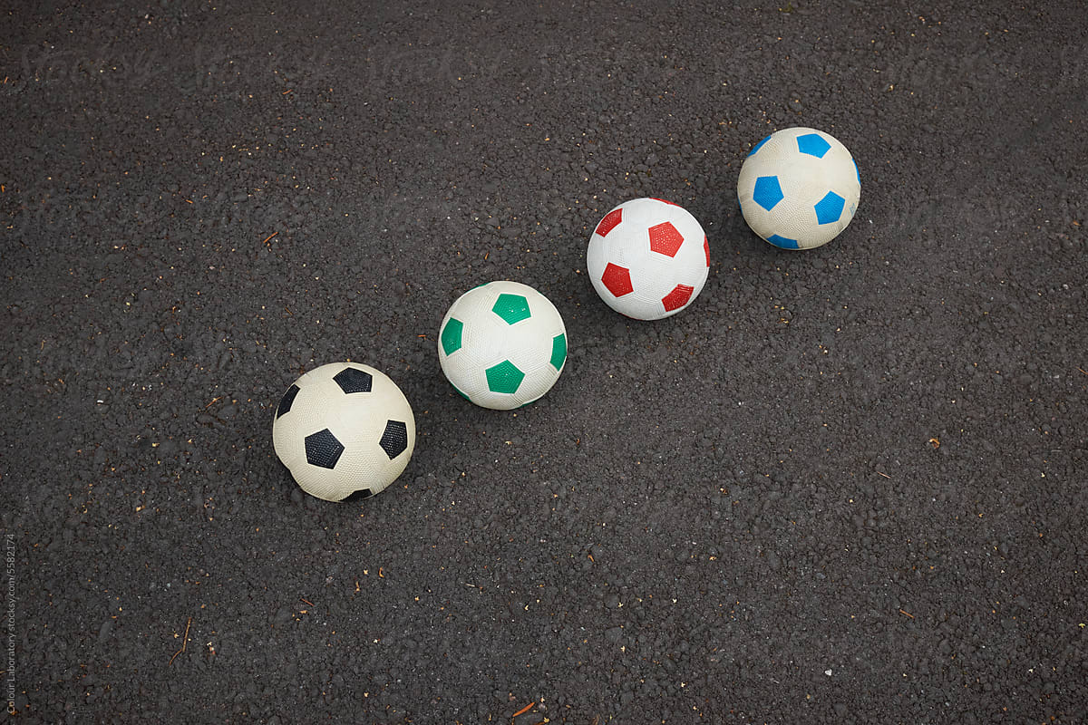 Minimal photo of colourful footballs with asphalt background