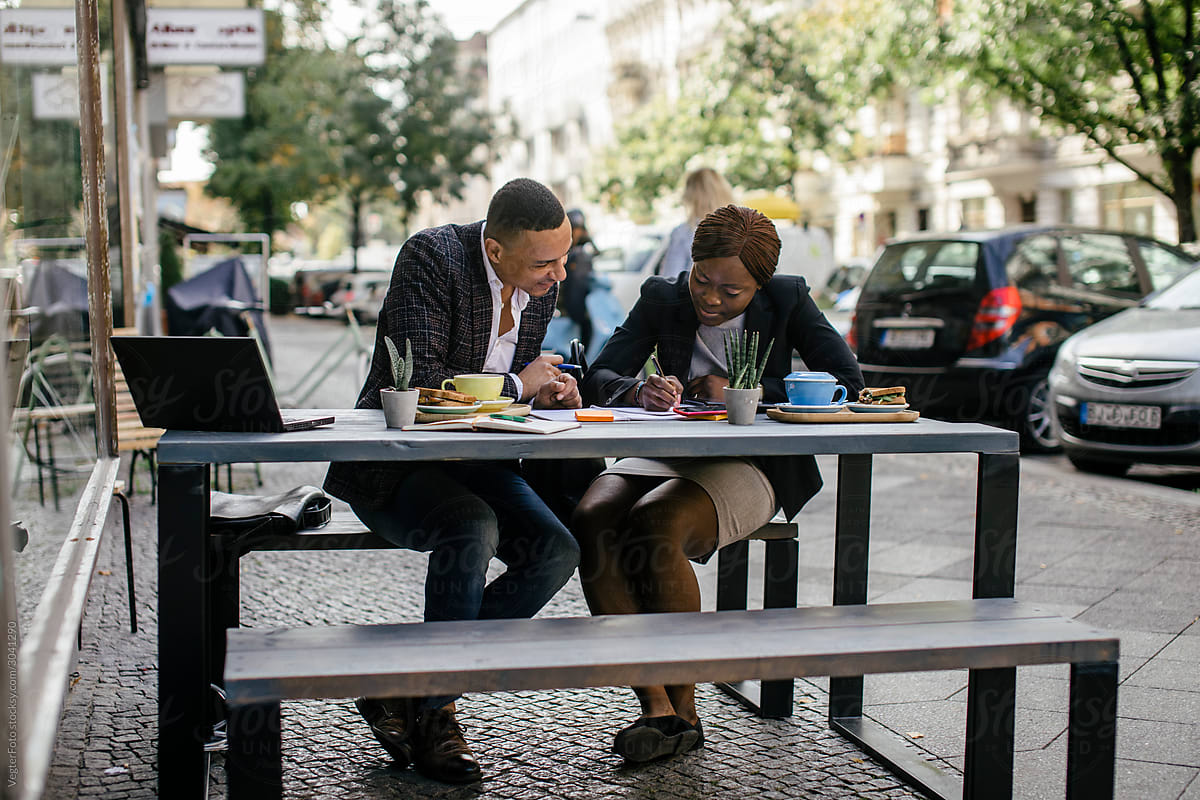 Two Business Colleagues Making Notes While Eating Breakfast Together