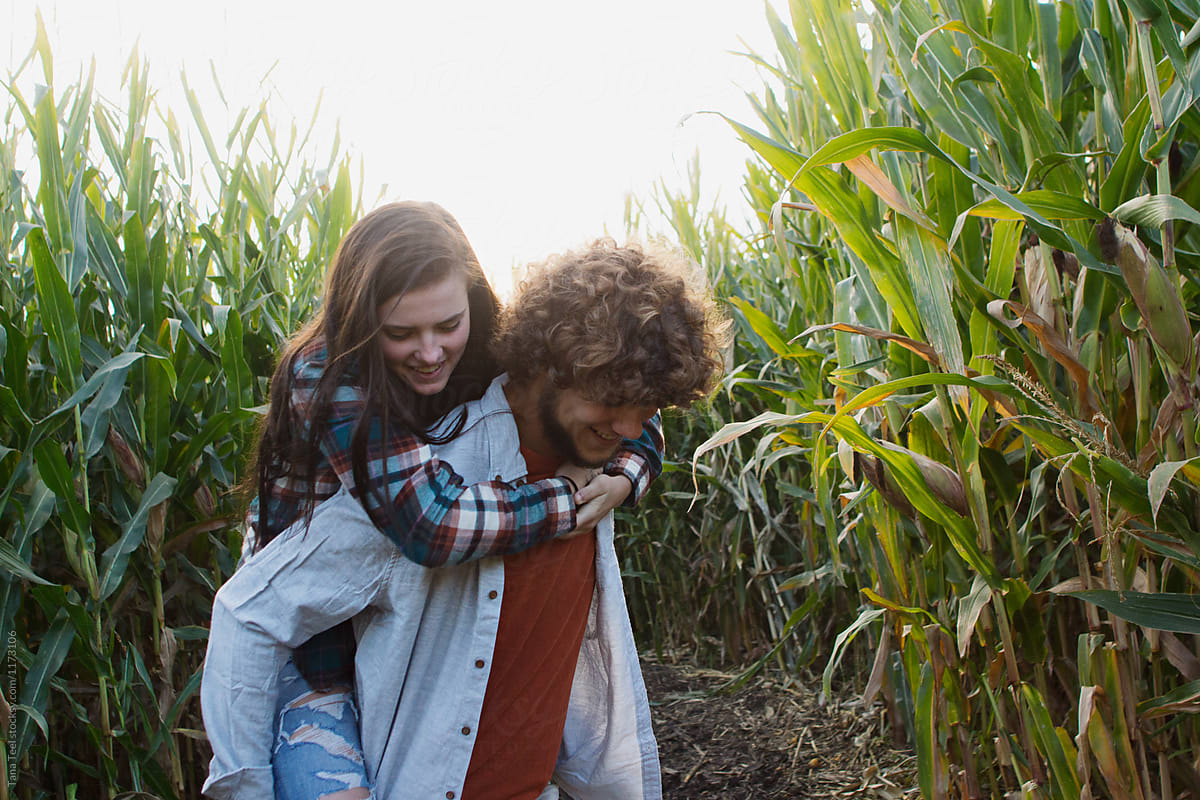 boy gives girl piggyback ride through corn maze