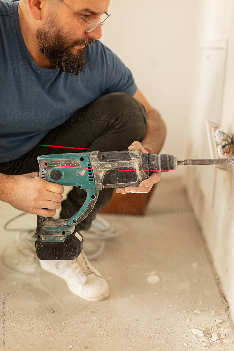Electrician drills a hole in the wall with a cordless machine
