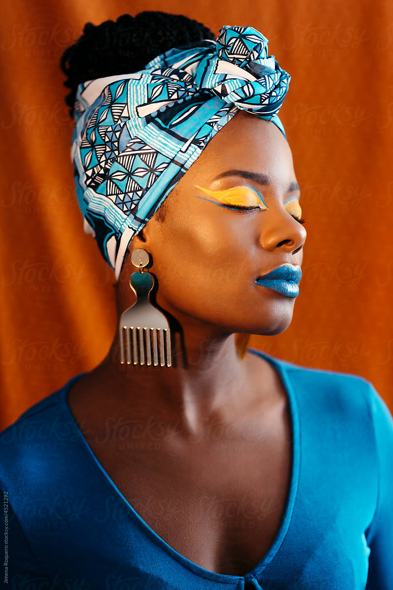 Woman with African print head band and creative makeup over orange