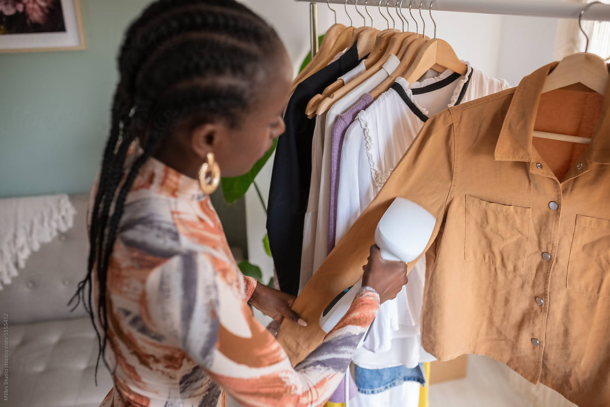 Black woman steaming shirt on rack