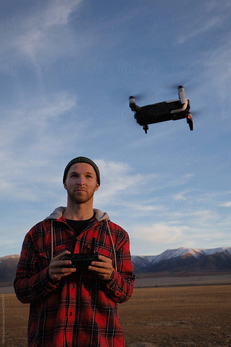 Guy traveler in a red jacket controls the drone