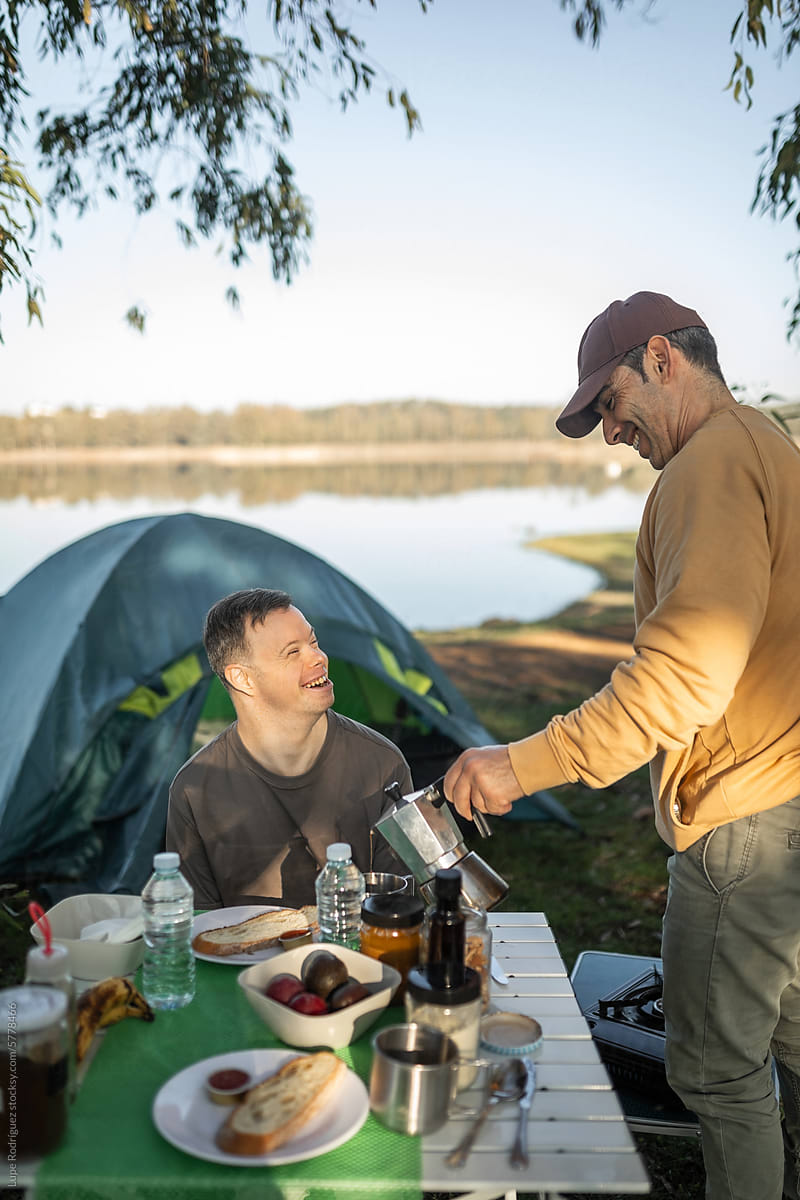man with down syndrome with his friend camping in nature