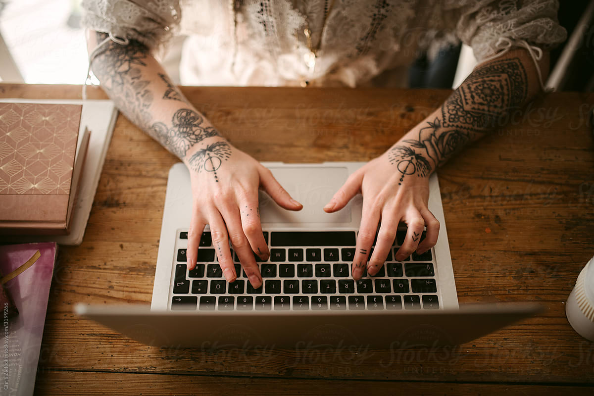 Crop female freelancer with tattoos typing on laptop