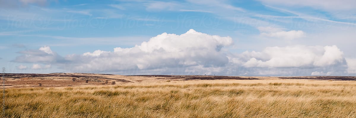 Blue sky and white clouds above sunlit moorland. Derbyshire, UK.