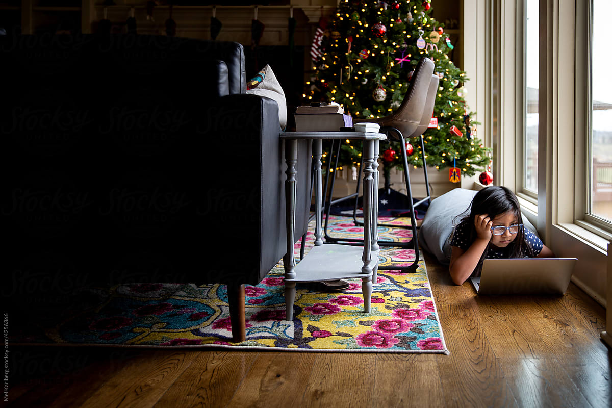 Young girl on computer in front of Christmas tree 2