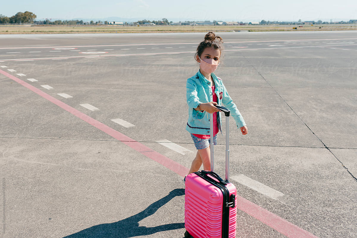Kid with trolley suitcase arriving to airport runway