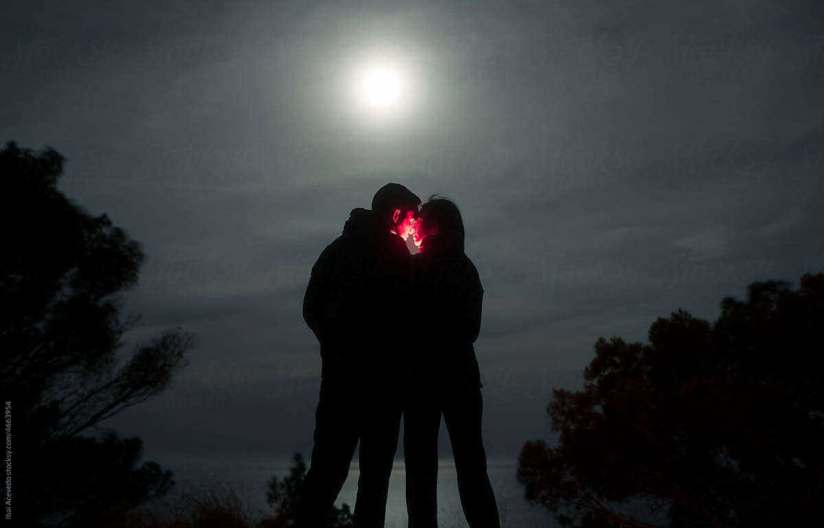 Couple kissing with red light under the moonlight