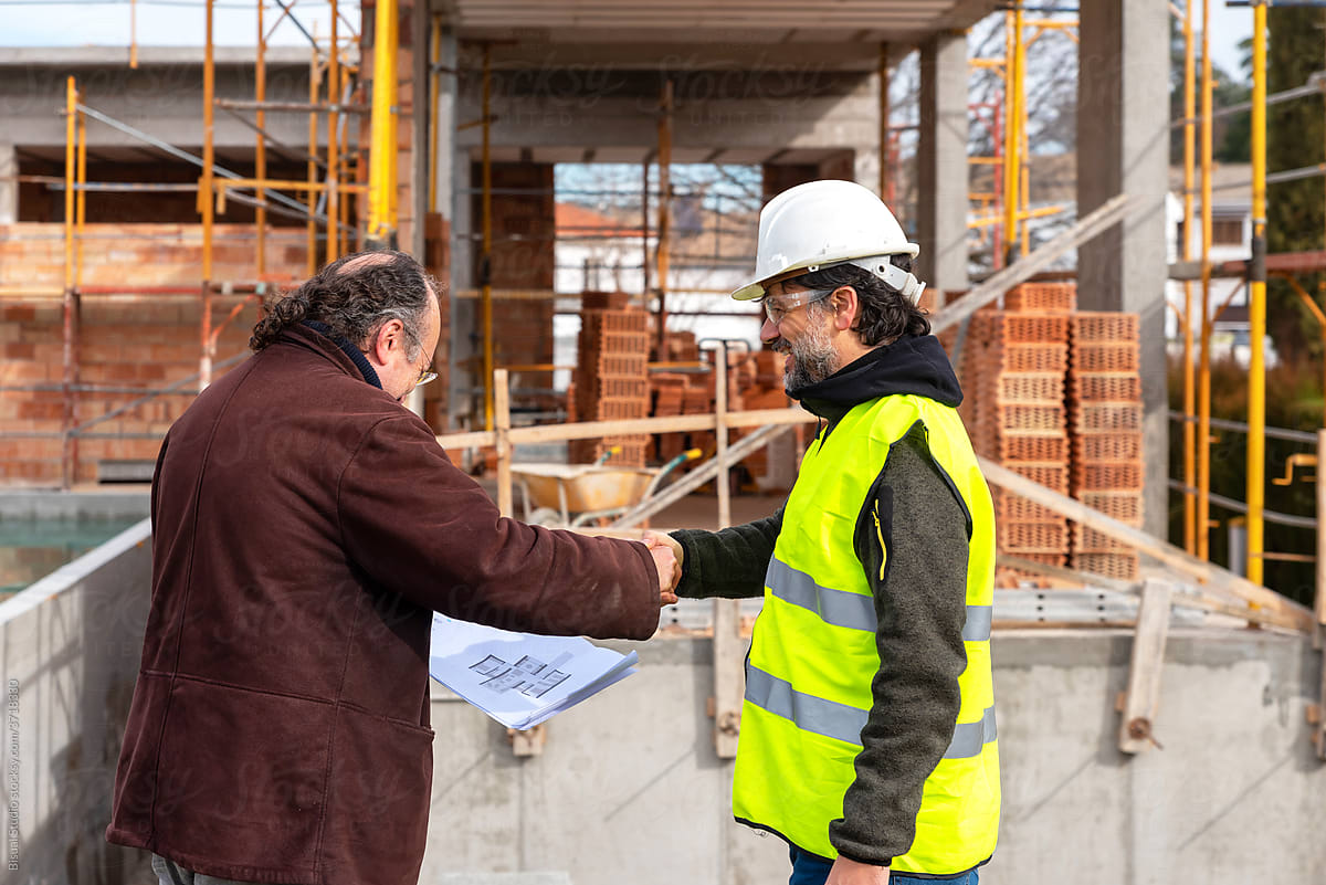 Contractor and engineer shaking hands on construction site