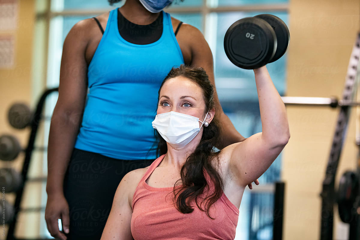 Gym: Trainer Helps Woman While Lifting Weights