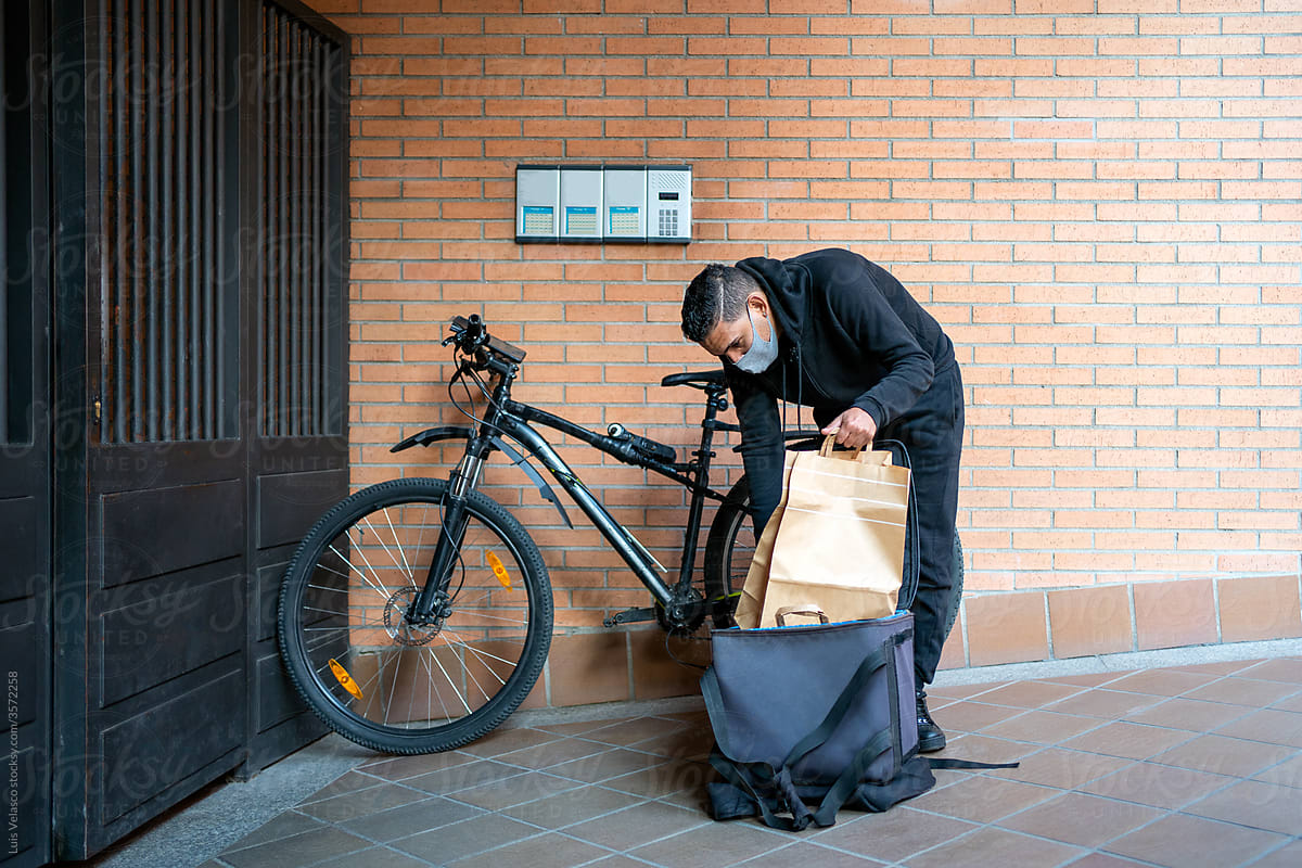 Courier With Bike Delivering Food To A House.