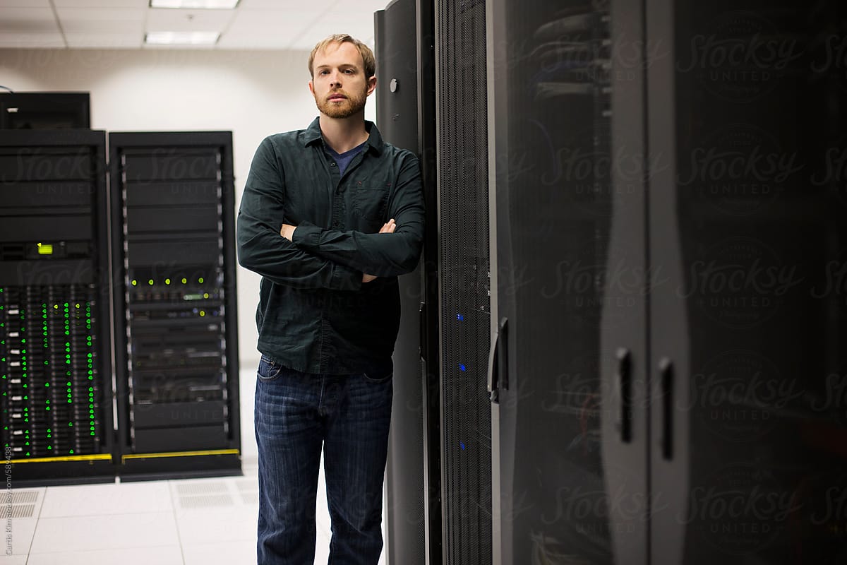 Young IT engineer standing near datacenter servers
