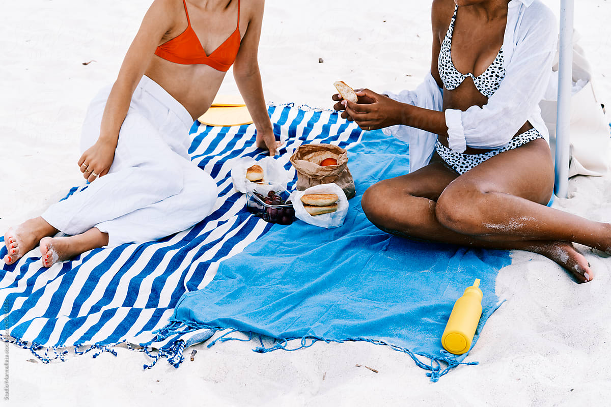 Crop women having picnic on beach