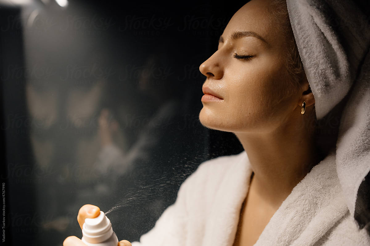 Woman spraying lotion on neck