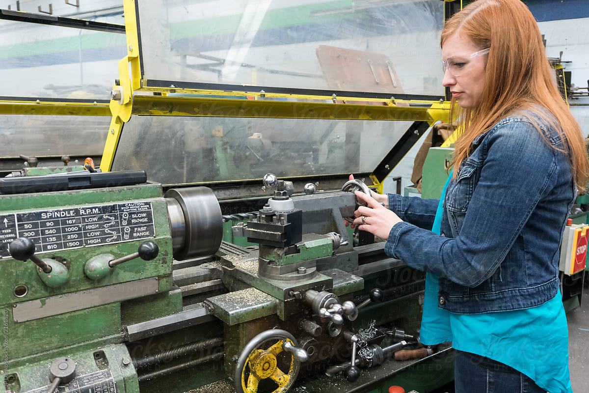 Female company executive hands-on with lathe in machine shop