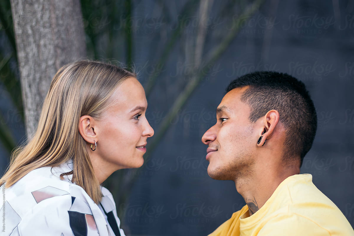 Multi-ethnic couple looking into each other\'s eyes outdoors