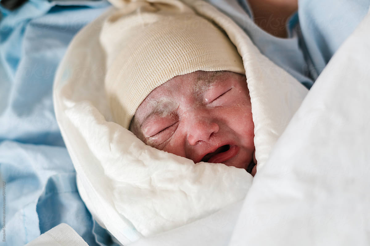 Unhappy newborn wrapped in warm blanket in clinic