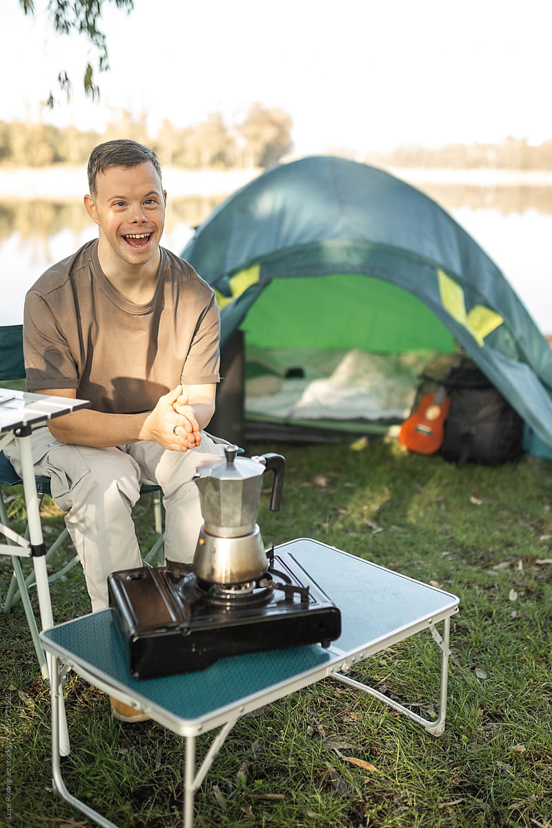 young man with down syndrome making camping coffee in nature