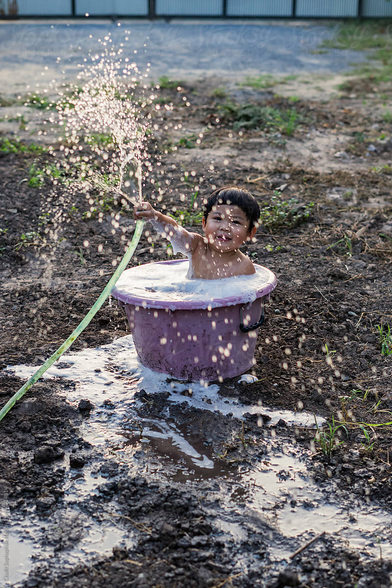Boy spraying water in a plastic basin