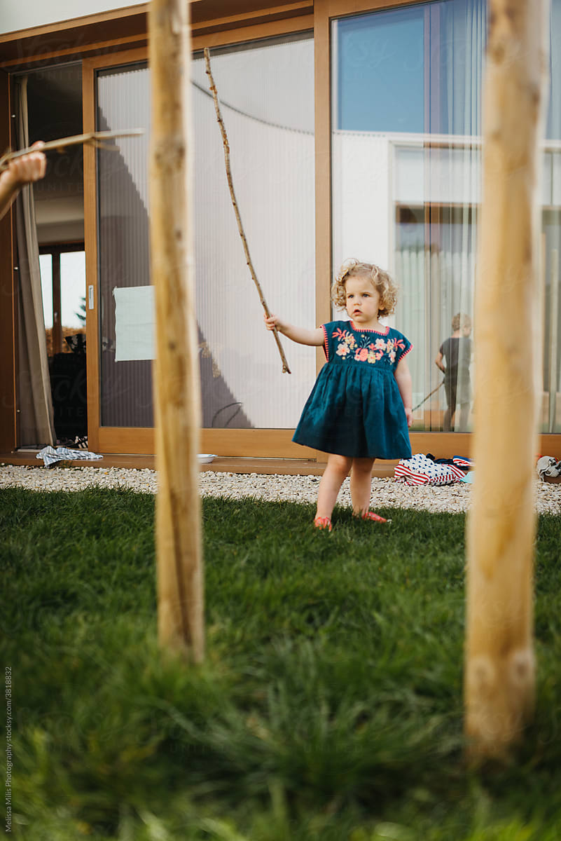 Little girl playing with wooden sticks in the garden