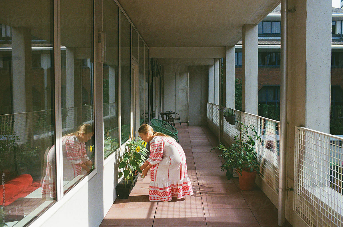 Girl cares for plants on modern balcony.