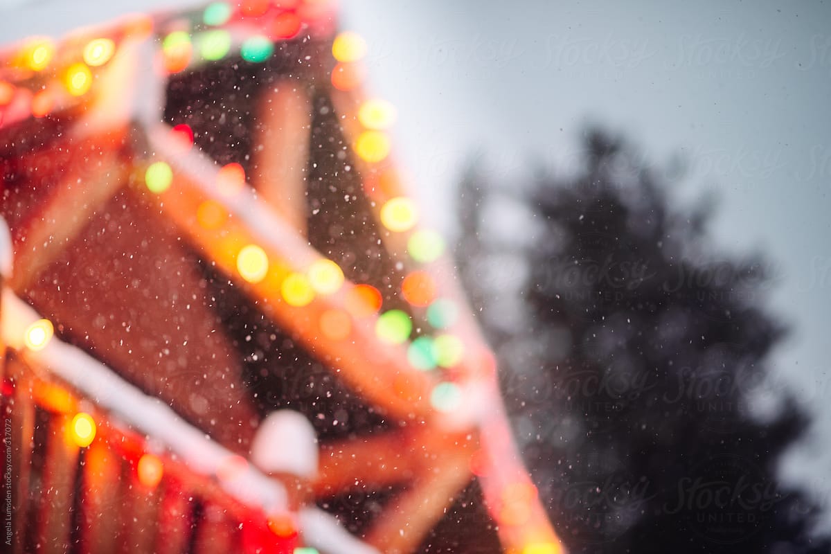 Snow falling on holiday lights of a ski log cabin