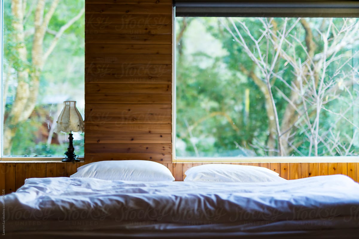 Bedroom with white bed and big window of view in forest