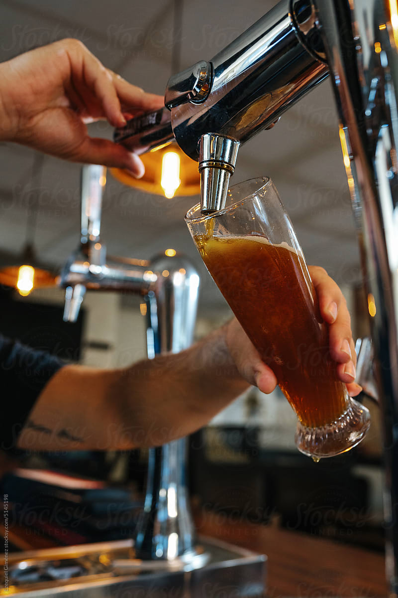 Crop barkeeper filling glass with beer