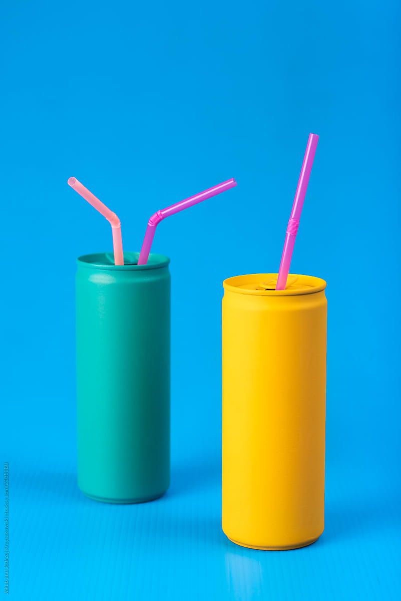 Yellow and turquoise cans with pink straws on blue background