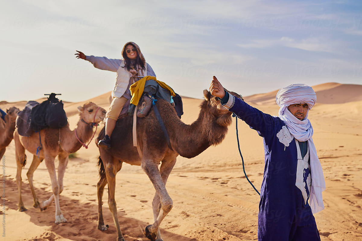 Local guide and smiling tourist enjoy the camel ride expedition.