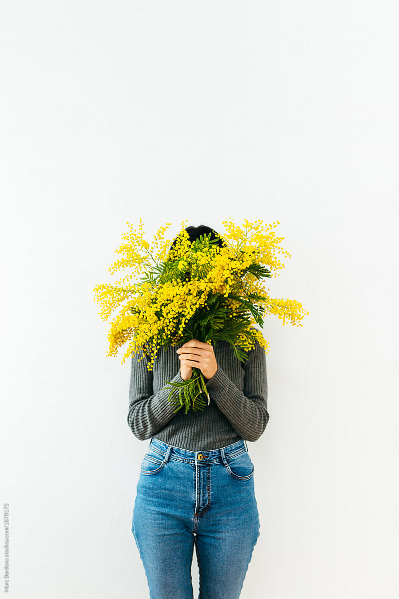 brunette girl covering her face with mimosa bouquet
