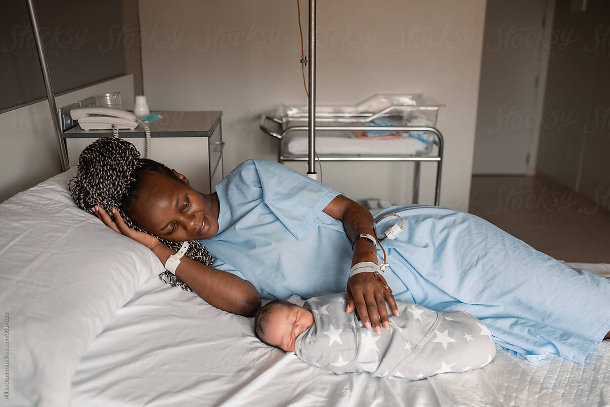 Black mom caressing newborn baby in hospital