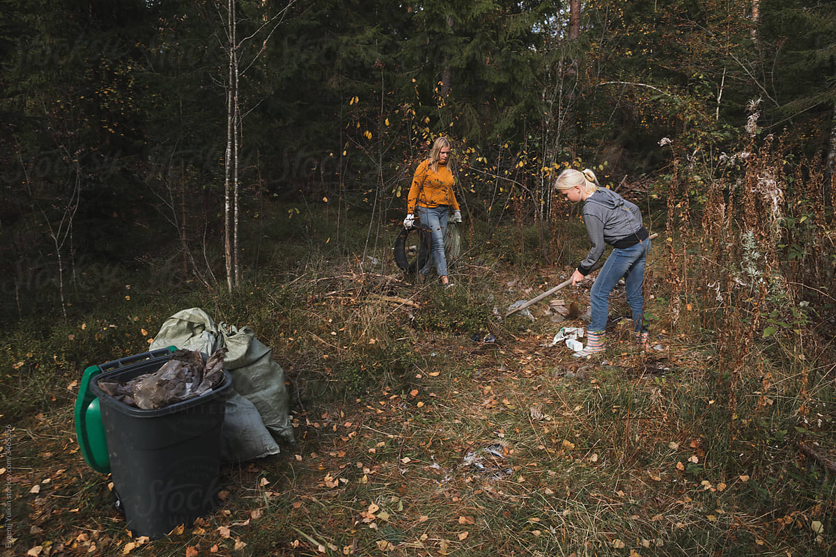 Woman  and her daughter collect plastic litter in the forest