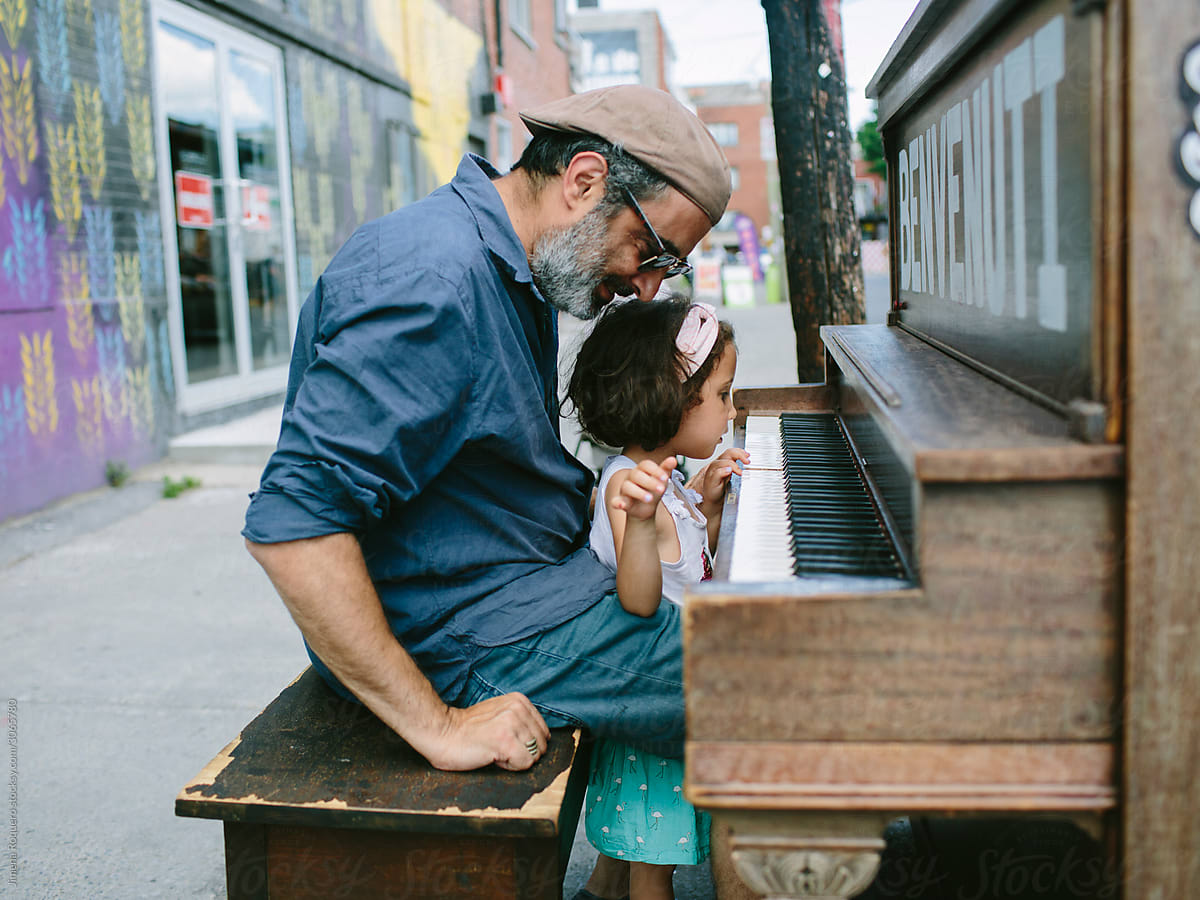 Father and daughter playing piano in the street