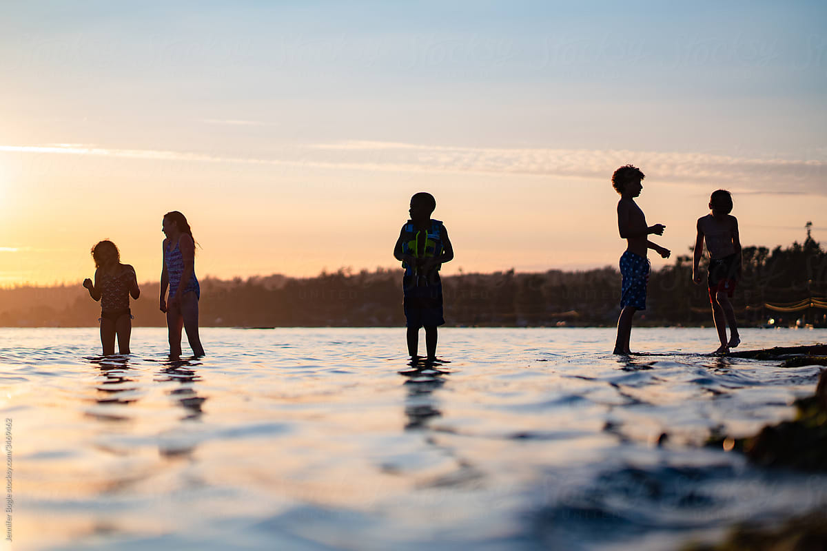 Five kids silhouetted against sunset in ocean