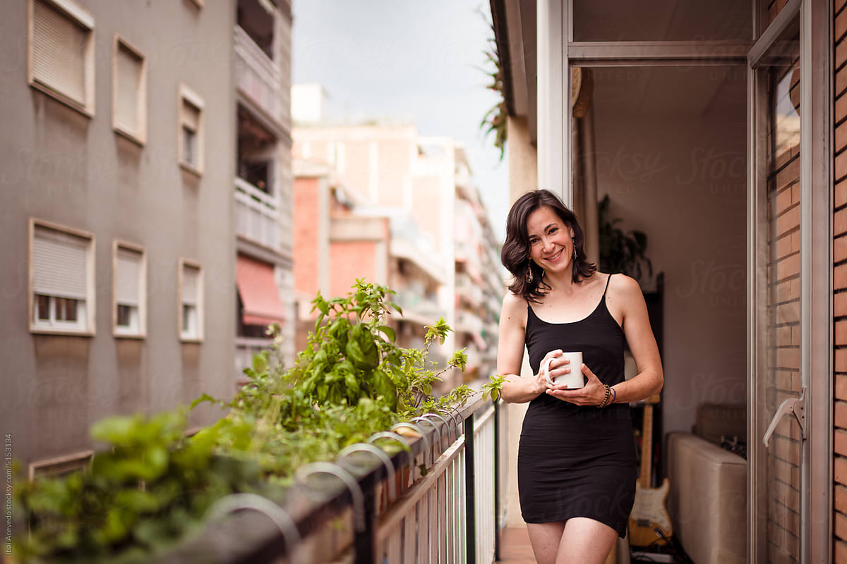 Smiling woman with coffee cup at city balcony