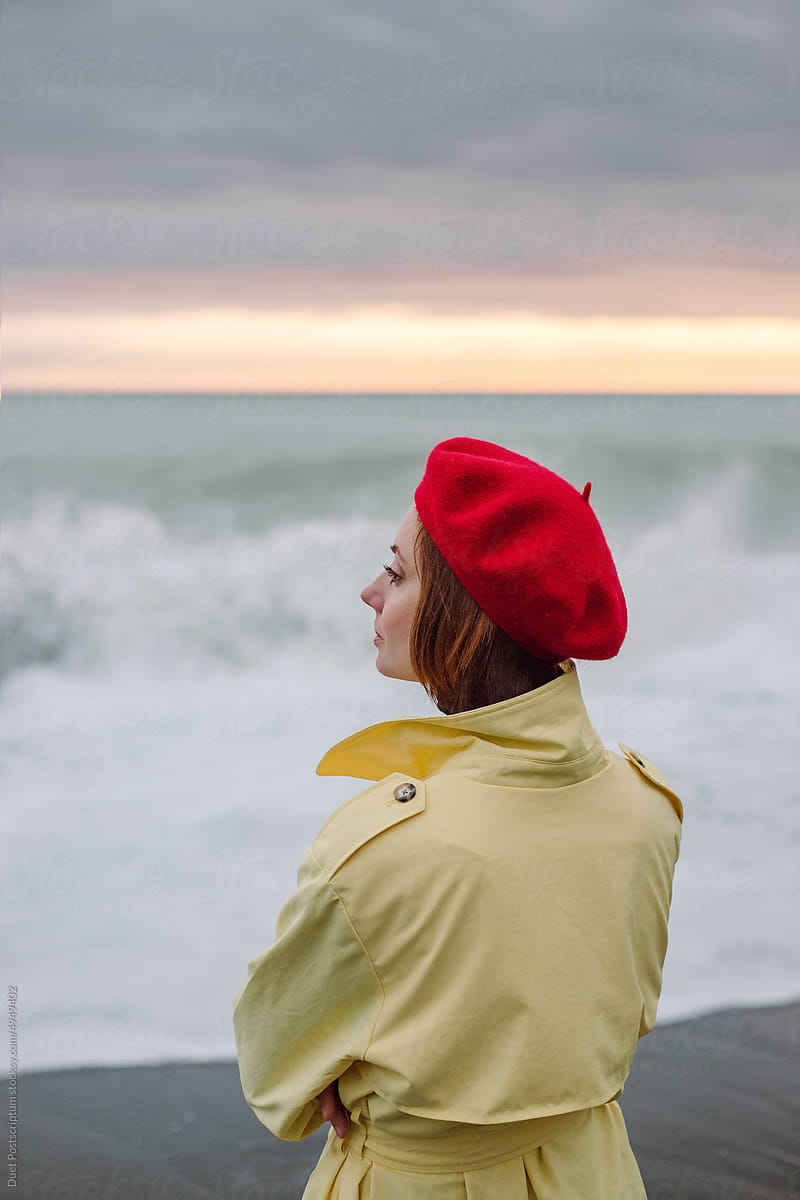 Profile portrait  of woman in an autumn raincoat by the sea