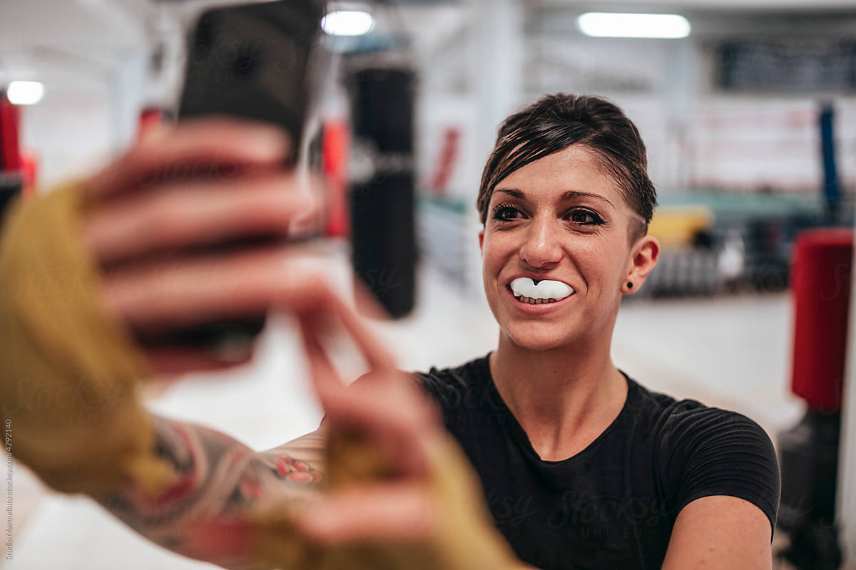 Cheerful sportswoman taking selfie in gym