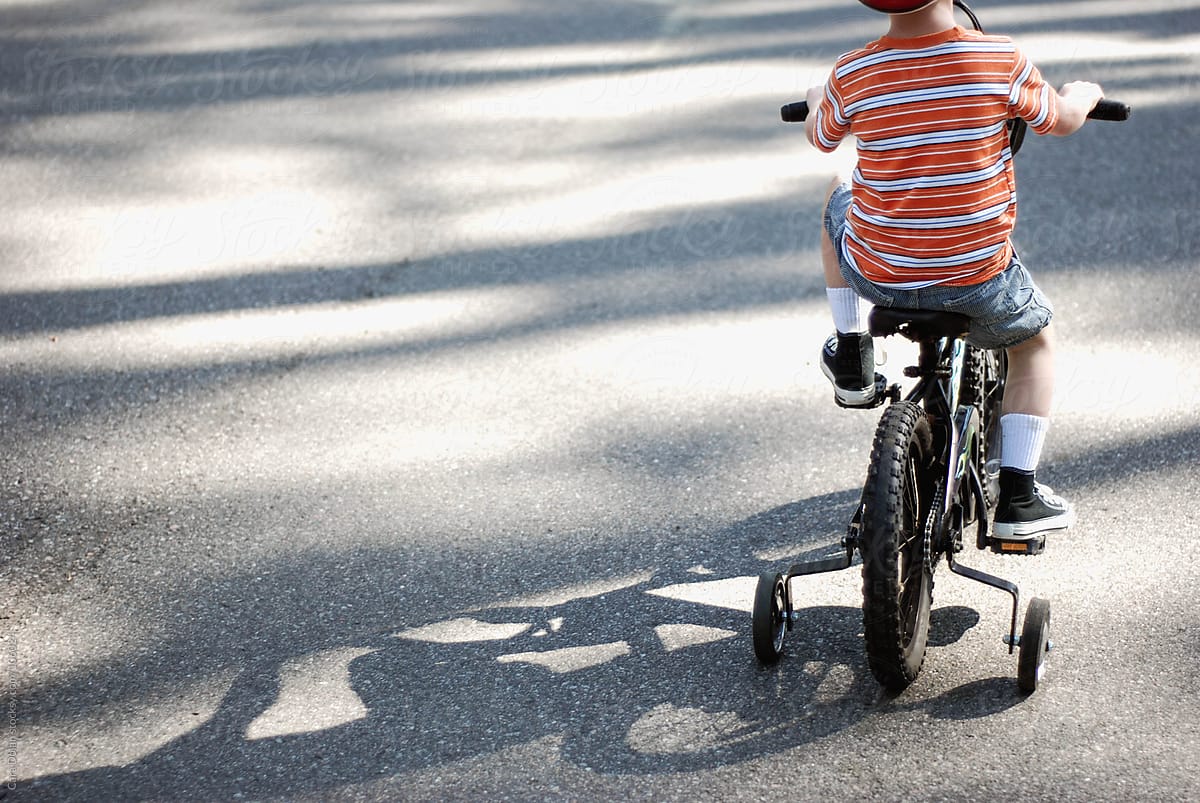 Child Rides Bike with Training Wheels on Bike Path