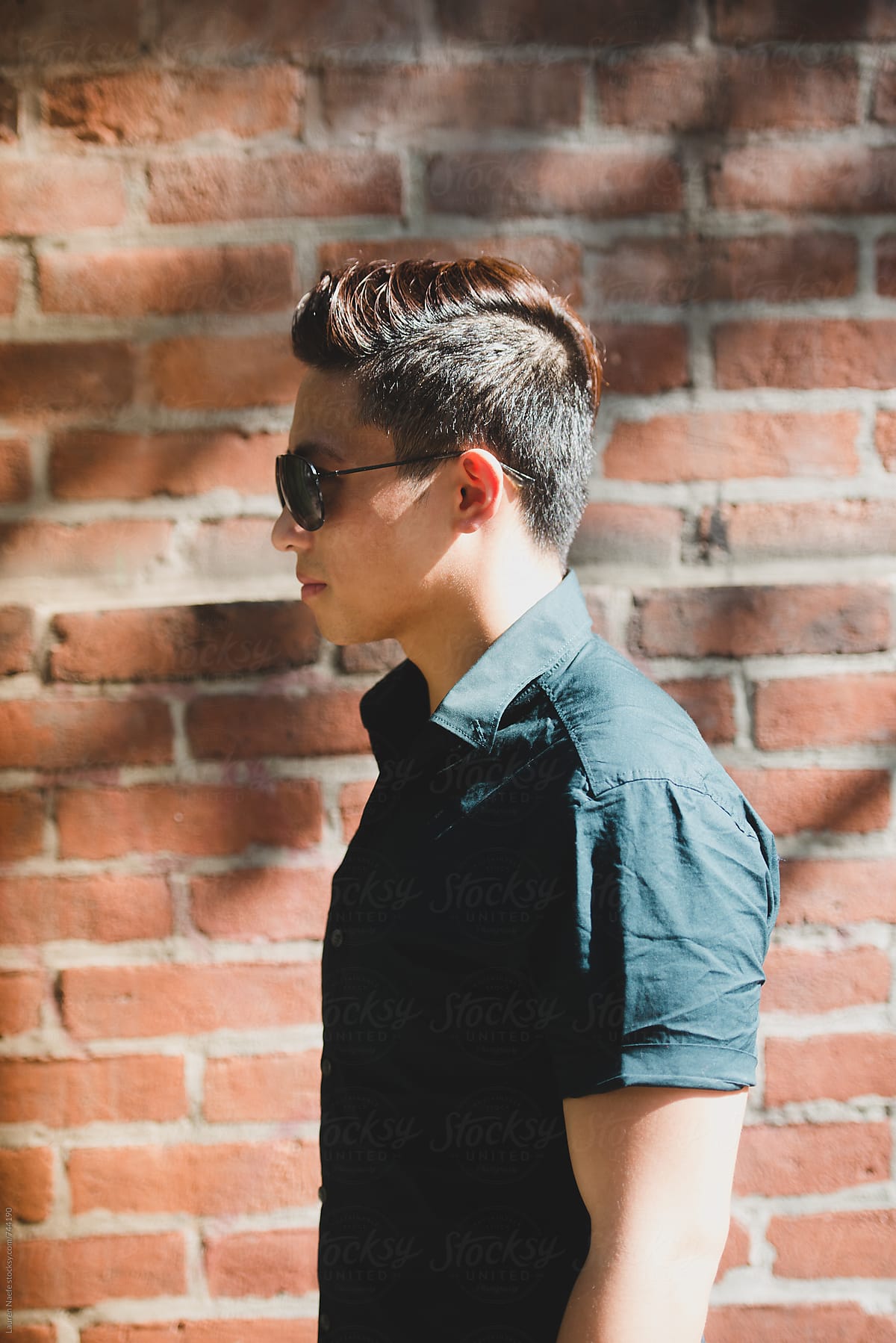 Young man standing against brick wall