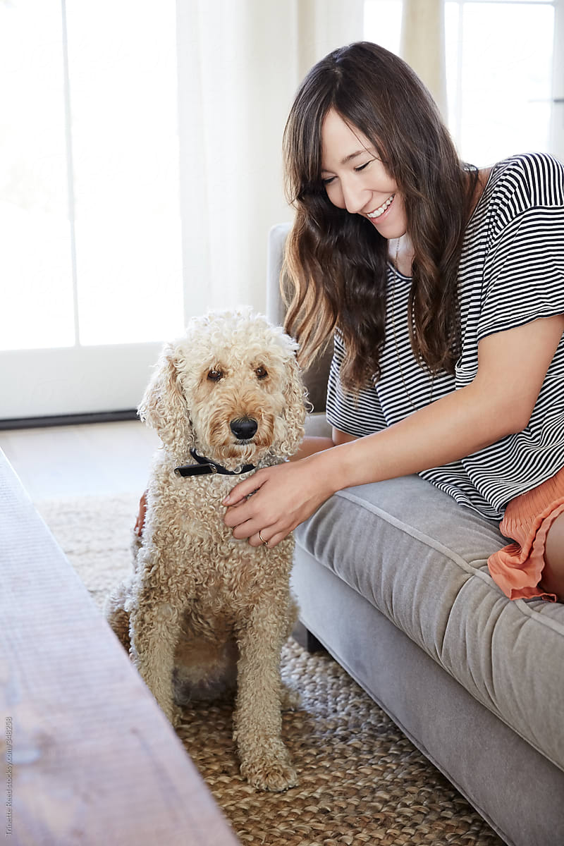 Woman relaxing and laughing in living room with her dog