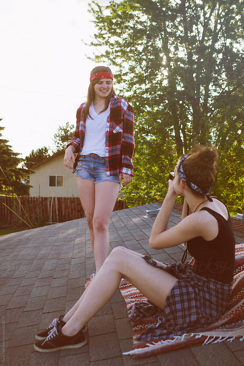  teen takes polaroid picture of friend while on a roof top by stocksy