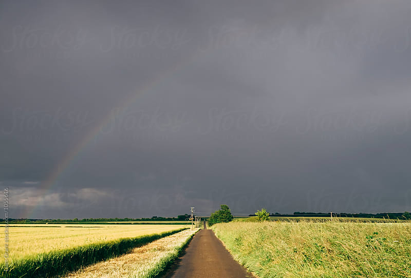 Storm clouds and rainbow over remote rural road. Norfolk, UK.