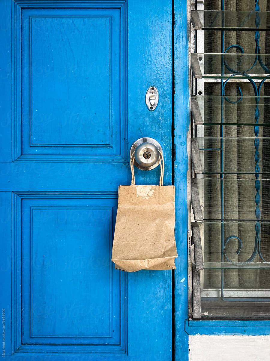 A little brown paper bag with a delivery hangs from an old blue door
